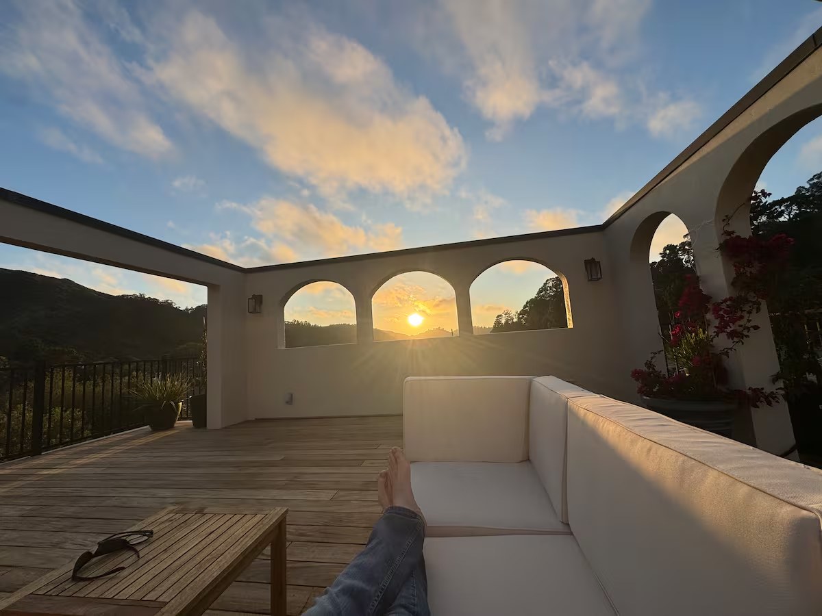 Rooftop deck at golden hour framed by white stucco arches with the Pacifica coastline beyond